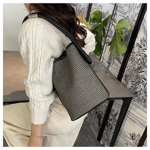 Vue détaillée de la texture tissée noir et blanc et de la bandoulière en cuir du sac seau