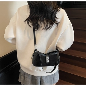 Detail of black quilted crossbody bag with silver twist lock and mixed leather texture