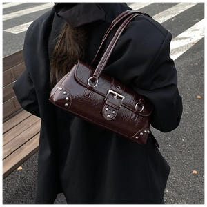 Detail of dark brown glossy leather shoulder bag with silver buckle on black blazer