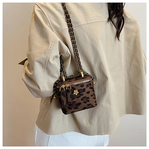 Gros plan du mini sac boîte léopard avec chaîne dorée et emblème de camélia chic