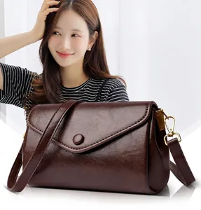 Detail shot of the vintage brown crossbody bag with glossy leather texture and round buckle