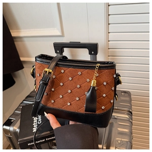 Detail of brown suede crossbody bag with rhinestone grid pattern and gold tassel