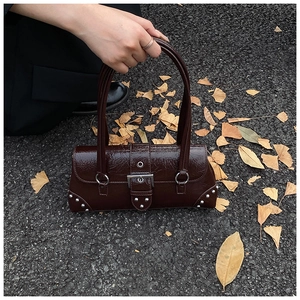 Detail of dark brown vintage oil wax leather handbag with glossy finish and silver studs