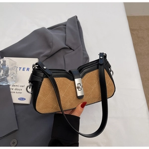 Close-up of contrast color baguette bag featuring brown suede and black leather texture