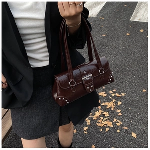Detail of burgundy patent leather handbag with silver buckles and rivets in street setting