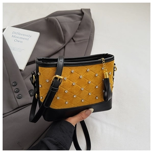 Close-up of yellow suede quilted crossbody bag with rhinestone studs and gold fringe detail
