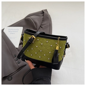 Detail of green quilted velvet crossbody bag with black trim and rhinestone accents
