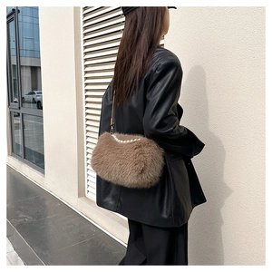 Detail view of brown plush crossbody bag with large pearl handle on black leather jacket