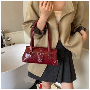 Detail of burgundy patent leather handbag with pleated texture and silver hardware