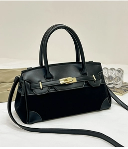 Détail de la texture cuir noir mat avec fermoir doré sur un sac à main de créateur