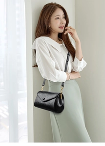 Detail of elegant black crossbody bag featuring gold hardware and premium leather texture