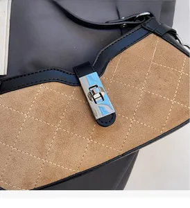Detail of tan suede bag with quilted stitching and polished silver twist lock clasp