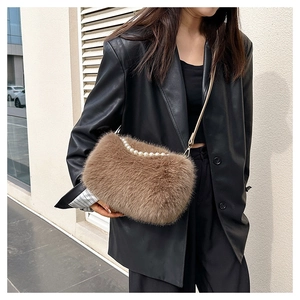 Detail of plush brown faux fur bag with elegant pearl handle and metal chain strap