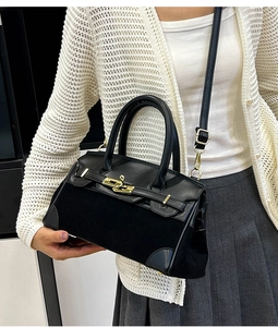 Gros plan du sac en cuir noir avec fermoir rotatif doré et bandoulière amovible