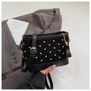 Close-up of black quilted suede bucket bag with rhinestone details and gold chain tassels
