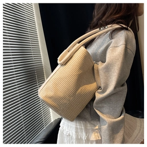 Vue détaillée d'un sac seau tressé beige avec texture montrant la finition de la bandoulière