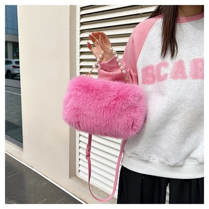 Detail view of pink faux fur bag with pearl handle and leather strap on model