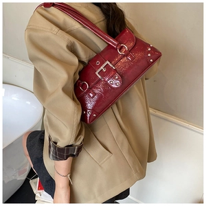 Detail of dark red crocodile pattern bag with silver buckle and rivets on model