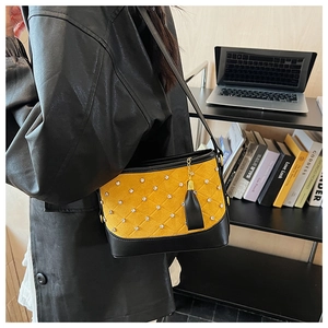 Detail view of a yellow suede crossbody bag with rhinestone quilting and tassel