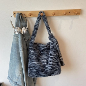 Detailed texture of fluffy black and grey striped faux fur tote bag hanging on a hook