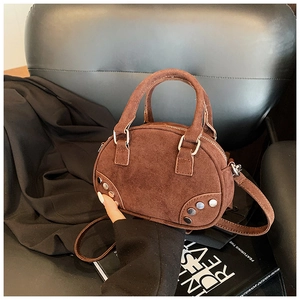 Detailed shot of a brown suede bowling bag with silver studs on a black leather chair