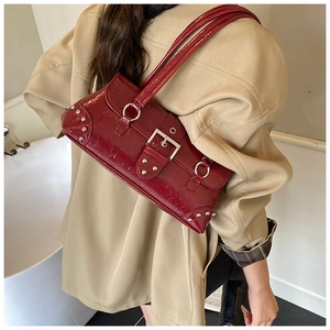 Detail of burgundy glossy patent leather shoulder bag with silver hardware on beige coat