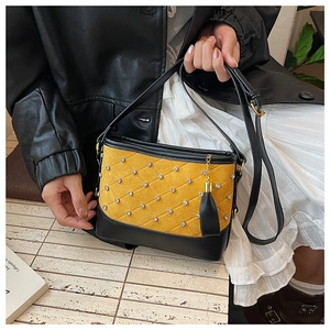 Detail of yellow quilted crossbody bag with rhinestone accents and leather tassel charm