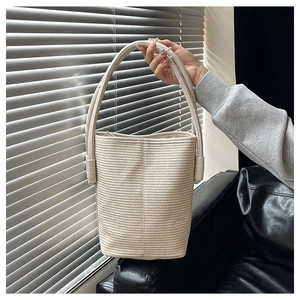Vue détaillée du sac seau tissé beige présentant des textures de corde horizontales
