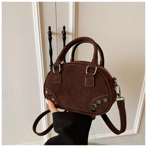Detail of dark brown suede bowling bag featuring vintage silver rivet studs on bottom sides