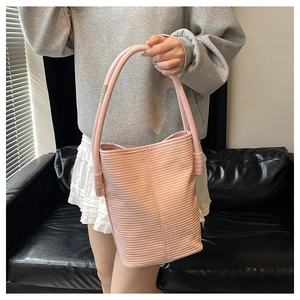 Détail d'un sac seau rose cylindrique avec texture rayée et bandoulière épaisse design