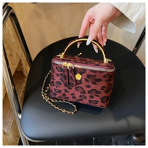 Détail du sac boîte léopard avec poignée en métal doré et emblème floral
