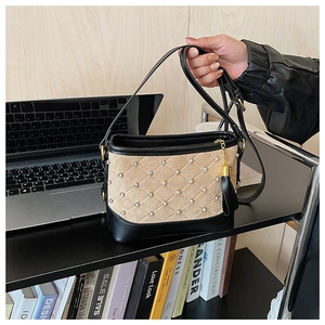 Detail of beige quilted crossbody bag with sparkling rhinestones and metal fringe