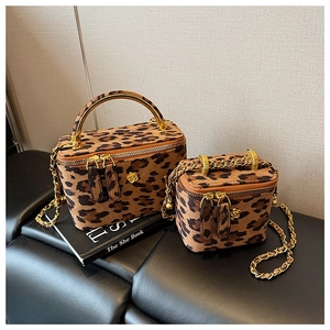 Détail du mini sac boîte léopard avec boucle camélia dorée et bandoulière chaîne