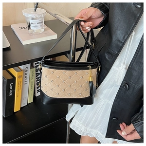 Detail view of quilted black leather and khaki suede shoulder bag with tassel and gold hardware