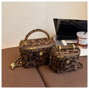 Détail de sacs boîtes à motif léopard avec logos camélia dorés et bandoulières chaînes