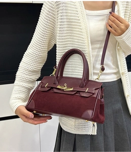 Détail du sac Kelly bordeaux avec fermoir rotatif doré et empiècement en daim