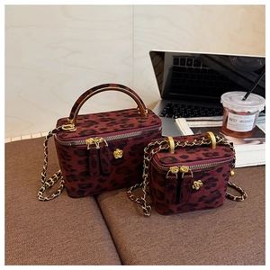 Détail de mini sacs boîte à imprimé léopard avec poignées dorées et bandoulière chaîne