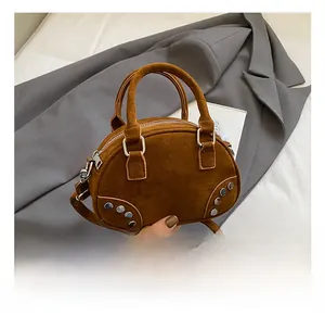 Close-up of brown suede bowling bag featuring silver rivets and fine matte texture