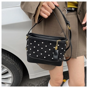 Detail of black quilted suede and smooth leather crossbody bag with golden hardware