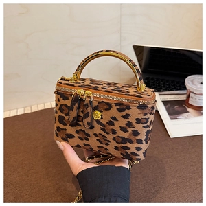 Détail du mini sac boîte léopard avec poignée en métal doré et breloque fleur
