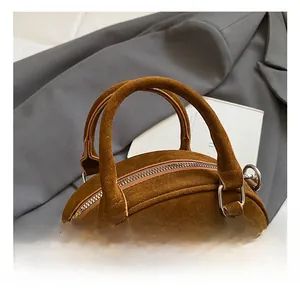 Close-up of brown suede bowling bag details with metal rivets and sturdy hand straps