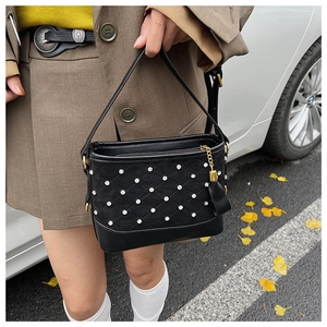 Detail of black suede quilted crossbody bag with crystal embellishments and golden tassel
