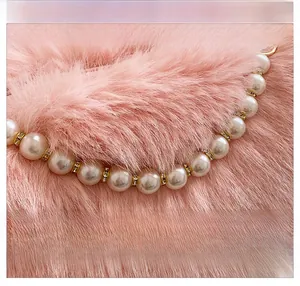 Close-up of pink faux fur bag featuring a pearl handle with sparkling rhinestone rings