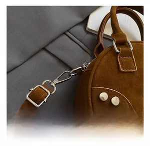 Detailed view of brown suede handbag featuring silver rivets and high-quality metal hooks