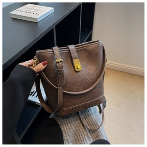 Détail d'un sac seau vintage en cuir marron avec un fermoir rotatif en métal doré chic