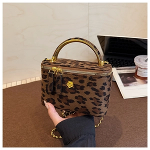 Détail du sac boîte léopard avec poignée en métal doré et logo emblème floral