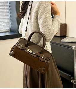 Détail du sac Kelly montrant le cuir mat marron foncé et la bandoulière en chaîne