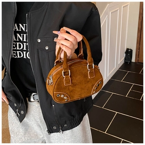 Detailed view of a brown suede mini bowling bag with silver studs and metal zippers