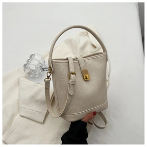 Détail du sac seau crème montrant la texture du simili cuir et les boucles dorées