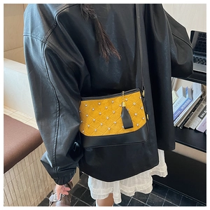 Detail of yellow and black crossbody bag with quilted patterns and tassel charm